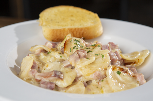 Creamy scalloped potato casserole filled with savory ham and cheese, served with garlic bread.