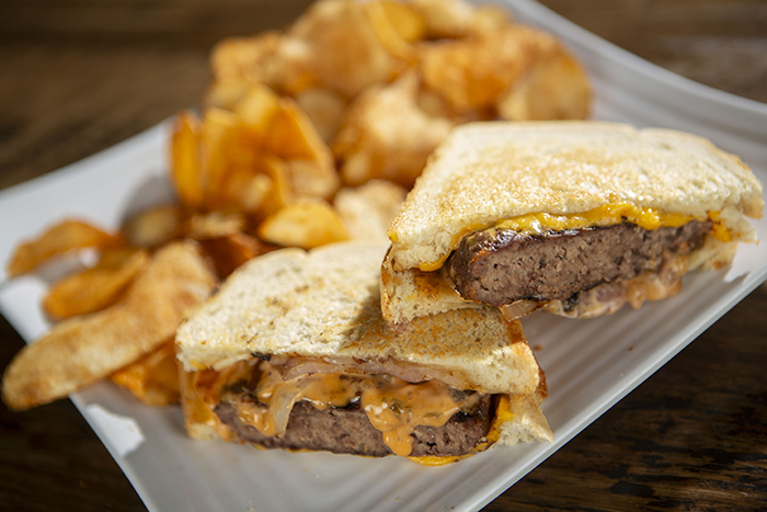 Our fresh burger patty topped with melted American cheese, sauteed onions and thousand island dressing nestled between 2 slices of grilled sourdough bread and served with a side of chips.