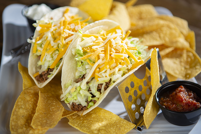2 beef soft shell tacos topped with lettuce and cheese served with chips and homemade salsa.